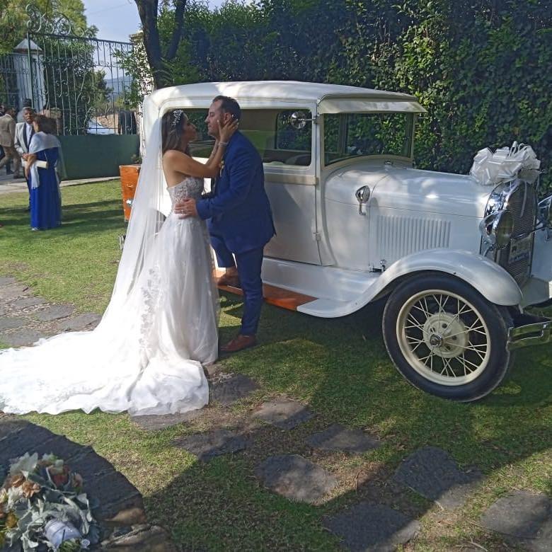Pareja de novios junto a auto antiguo blanco